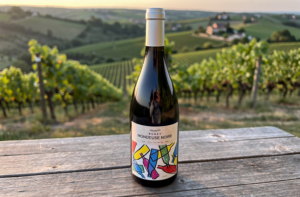 Bouteille de vin Mondeuse Noire du Bugey sur une table en bois dans un vignoble.